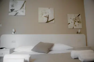 a bedroom with a white bed with three pictures on the wall at Anna Guest House in Rome
