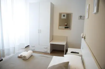 a white bedroom with a bed and a mirror at Anna Guest House in Rome