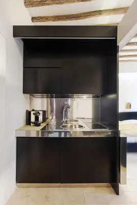 a kitchen with black cabinets and a sink at Oro in Rome