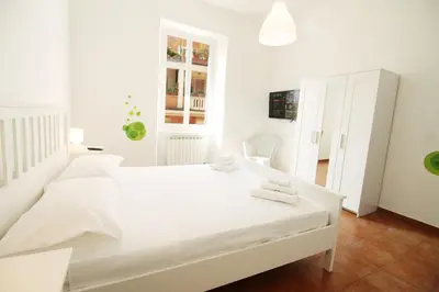 a white bedroom with a large white bed with white pillows at Walk to the Colosseum from your Family Apt in Rome