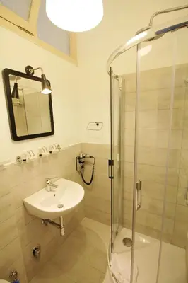 a bathroom with a sink and a glass shower at Walk to the Colosseum from your Family Apt in Rome
