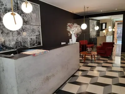 a lobby with a reception counter and red chairs at Navona Theatre Hotel in Rome
