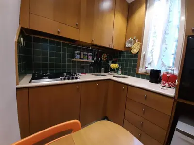 a kitchen with wooden cabinets and green tiles at FamilyBed Roma Monteverde-Vaticano in Rome
