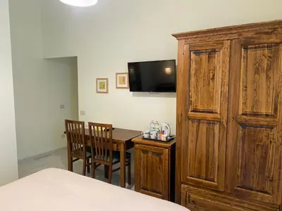 a bedroom with a table and a tv and a wooden cabinet at Guest House Laocoonte in Rome