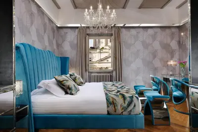 a bedroom with a bed with blue chairs and a chandelier at Lifestyle Suites Rome in Rome