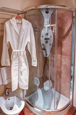 a shower stall with a white robe and a sink at Good Life Monti in Rome