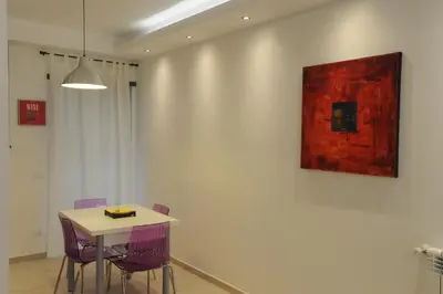 a table with purple chairs and a painting on a wall at Kings Of Rome Apartments in Rome
