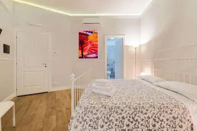 a white bedroom with a bed and a painting on the wall at Un Attimo A Roma B&B in Rome