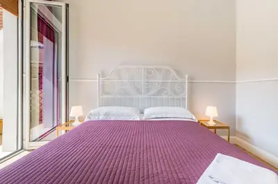 a bedroom with a large purple bed with two lamps at Un Attimo A Roma B&B in Rome
