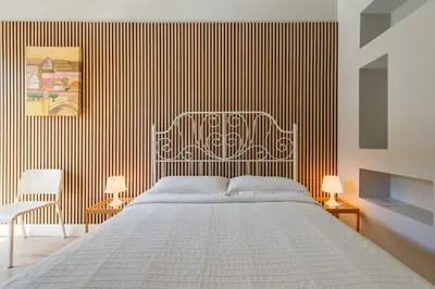 a bedroom with a white bed and a striped wall at Un Attimo A Roma B&B in Rome