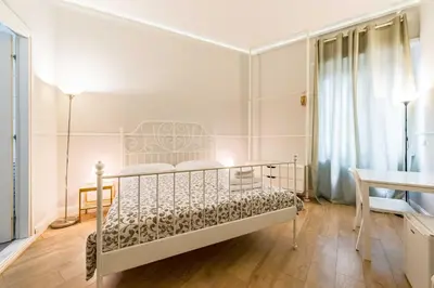 a white bedroom with a bed and a desk at Un Attimo A Roma B&B in Rome