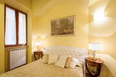 a bedroom with a white bed with two tables and two lamps at Impero Vaticano Navona Apartment in Rome