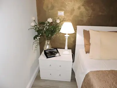a table with a lamp and a vase of flowers on a bed at Anfiteatro Suite in Rome