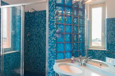 a blue tiled bathroom with a sink and a shower at La Dolce Vista Trastevere in Rome