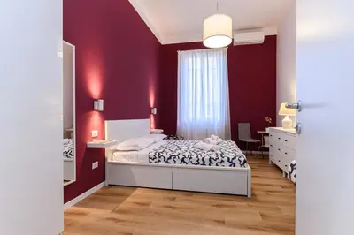a bedroom with a bed and a red wall at Stazione Vaticana 5 Apartment in Rome