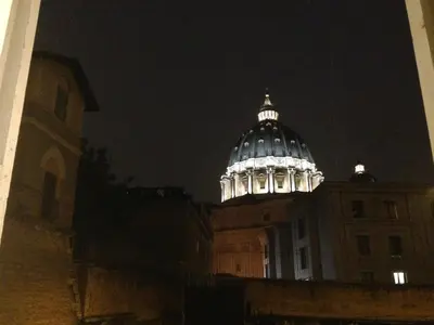 a building with a domed roof at night at Stazione Vaticana 5 Apartment in Rome