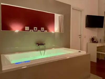 a bath tub with green water in a bathroom at Le Coq Suites in Rome