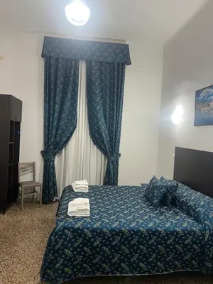 a bedroom with a bed with blue sheets and a window at Ines Downtown B&B in Rome