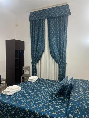 a bedroom with a blue bed with blue curtains at Ines Downtown B&B in Rome