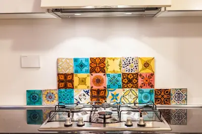 a kitchen with a stove with colorful tiles on the wall at Wake At Rome in Rome
