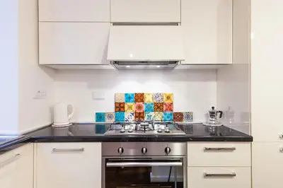 a kitchen with white cabinets and a stove top oven at Wake At Rome in Rome