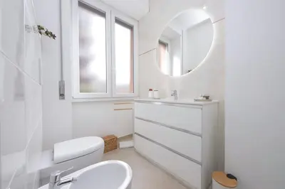 a white bathroom with a sink and a mirror at Nancy Bleisure Suite by DomusDimore in Rome