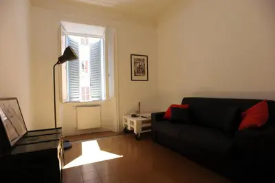 a living room with a black couch and a window at Domus Farnese in Rome