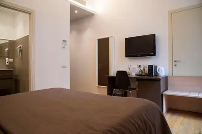 a hotel room with a bed and a desk and a television at Rome Armony Suites in Rome