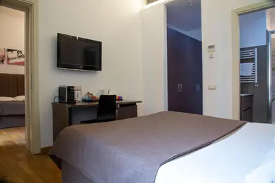a hotel room with a bed and a desk and a tv at Rome Armony Suites in Rome