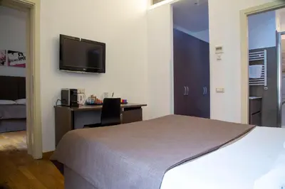 a hotel room with a bed and a desk and a tv at Rome Armony Suites in Rome