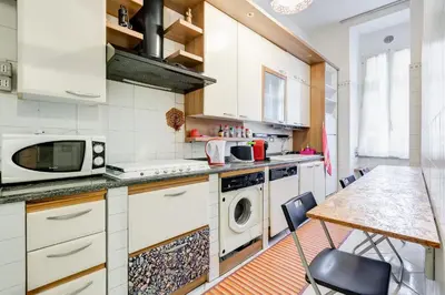 a kitchen with white appliances and a table with chairs at Casa Vacanza Home Sweet Home di Fatha in Rome