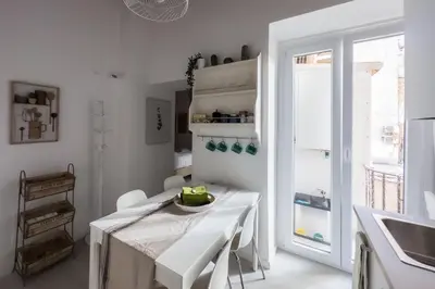 a white kitchen with a white table and a window at White Ostilia Apartments in Rome