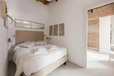a white bedroom with a bed and a brick wall at White Ostilia Apartments in Rome