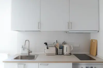 a kitchen with white cabinets and a sink at White Ostilia Apartments in Rome