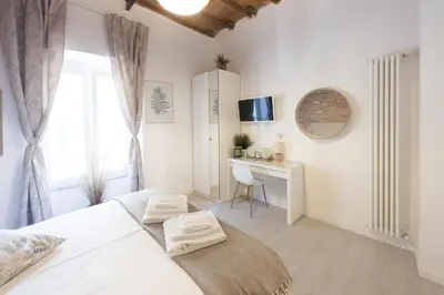 a white bedroom with a bed and a desk at White Ostilia Apartments in Rome