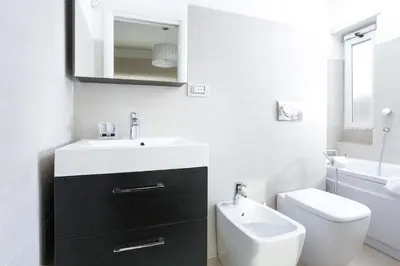 a white bathroom with a sink and a toilet at Enjoy the Sunset on Your Vatican Terrace in Rome