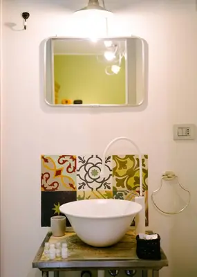 a bathroom with a bowl on a table with a mirror at Terrazza Munira Trastevere in Rome