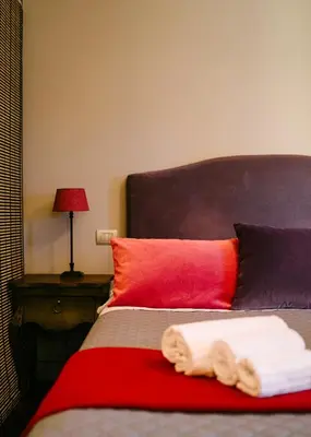 a bed with two towels on it with a red pillow at Terrazza Munira Trastevere in Rome