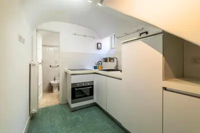 a small kitchen with white cabinets and a green floor at Tipico appartamento nel cuore di Trastevere in Rome