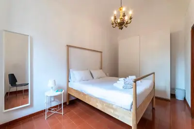 a bedroom with a bed and a mirror and a chandelier at Tipico appartamento nel cuore di Trastevere in Rome