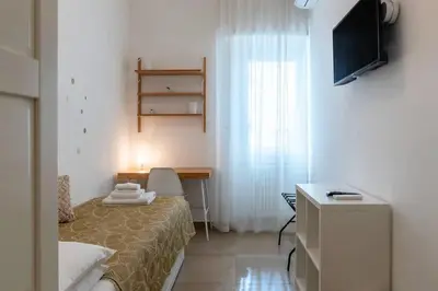 a room with a bed and a desk and a television at Nuovo e ampio appartamento vicino metropolitana in Rome