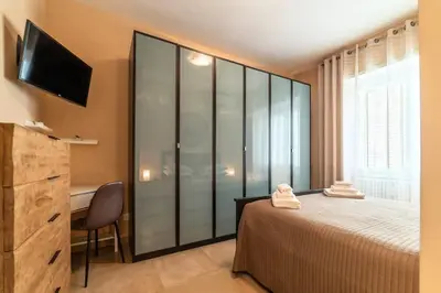 a bedroom with a bed and a desk and a television at Nuovo e ampio appartamento vicino metropolitana in Rome