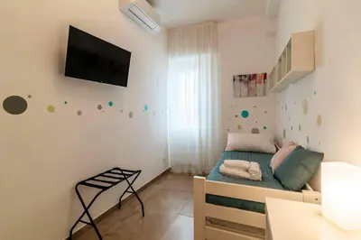 a small bedroom with a bed and a tv on the wall at Nuovo e ampio appartamento vicino metropolitana in Rome