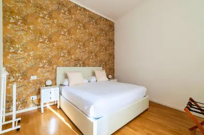 a bedroom with a white bed and a floral wallpaper at Appartamento nel cuore del pittoresco Pigneto in Rome