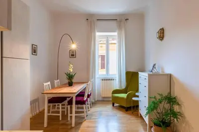 a kitchen and dining room with a table and a green chair at Appartamento nel cuore del pittoresco Pigneto in Rome