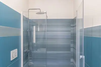 a bathroom with a glass shower with blue tiles at Nuovo appartamento ben collegato con il centro in Rome