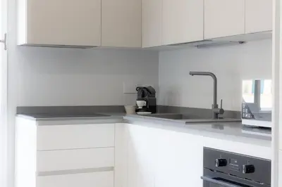 a kitchen with white cabinets and a sink at Nuovo appartamento ben collegato con il centro in Rome