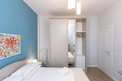 a white bedroom with a bed and a mirror at Nuovo appartamento ben collegato con il centro in Rome