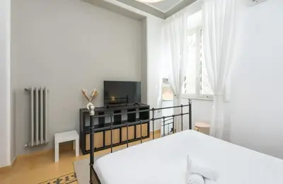 a bedroom with a bed and a flat screen tv at 4 comodi posti letto con giardino al Colosseo in Rome