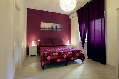a bedroom with a bed with red walls and purple curtains at Appartamenti Romatour in Rome